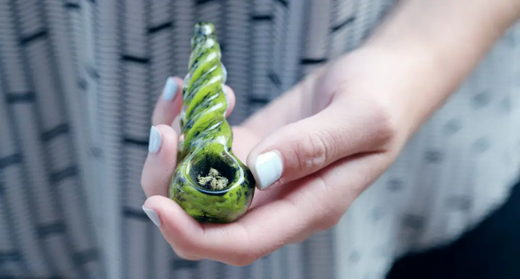 Holding a pipe with marijuana
