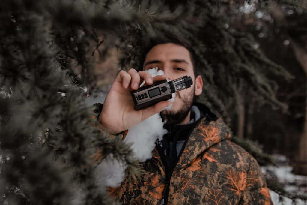 Man in brown and black jacket holding vape