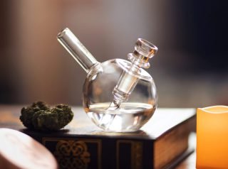 Clear glass pipe on brown wooden table with weed