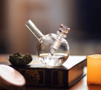 Clear glass pipe on brown wooden table with weed